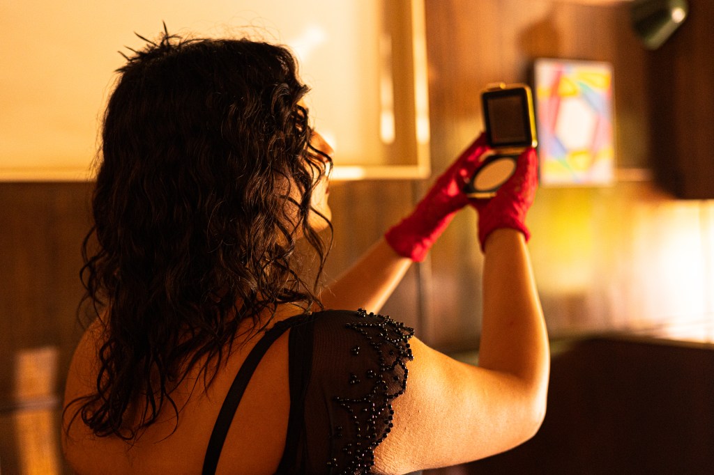 An image of Giulia, in costume as Lady Macbeth, holding a pocket mirror up and looking at her reflection.